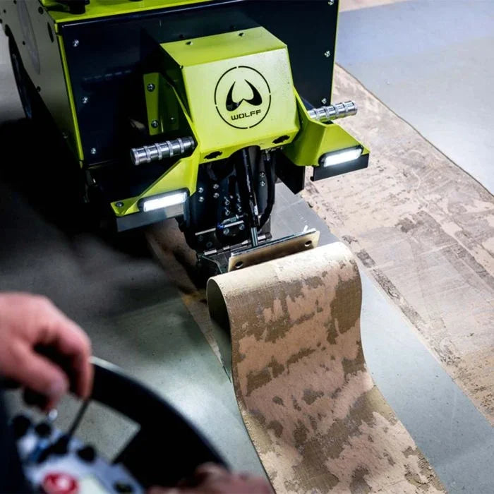 Wolff battery ride-on floor stripper removing old carpet from a concrete floor.