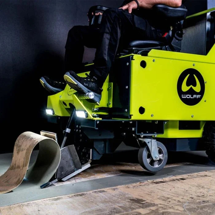 Wolff battery ride-on floor stripper machine removing old flooring material.